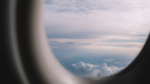 view outside aircraft window with blue sky and clouds