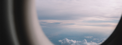 view outside aircraft window with blue sky and clouds