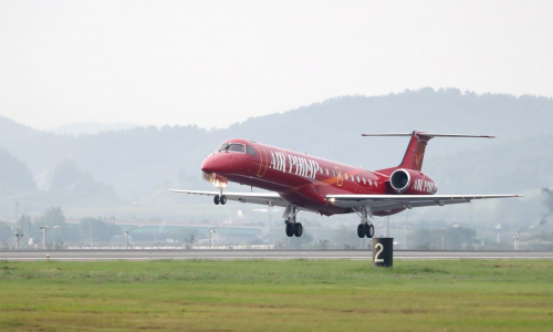 red embraer erj commercial airline landing on runway